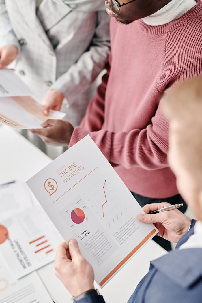 A group of professionals reviewing financial reports with graphs and statistics at a meeting.